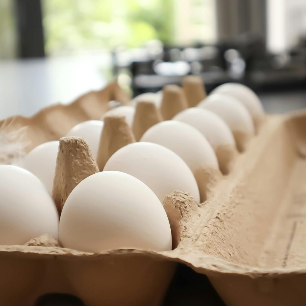 Fresh white eggs in a cardboard carton on a kitchen counter.